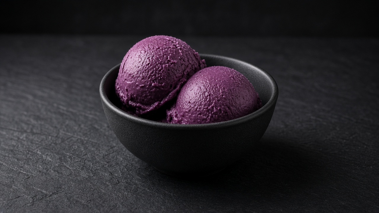 Two scoops of deep purple blackberry frozen yoghurt in a black bowl.